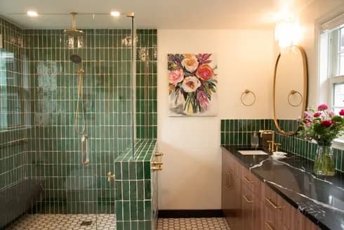 Primary bathroom with green tile shower and brass fixtures