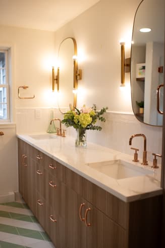 Hall bath vanity with rose gold fixtures and arched mirrors